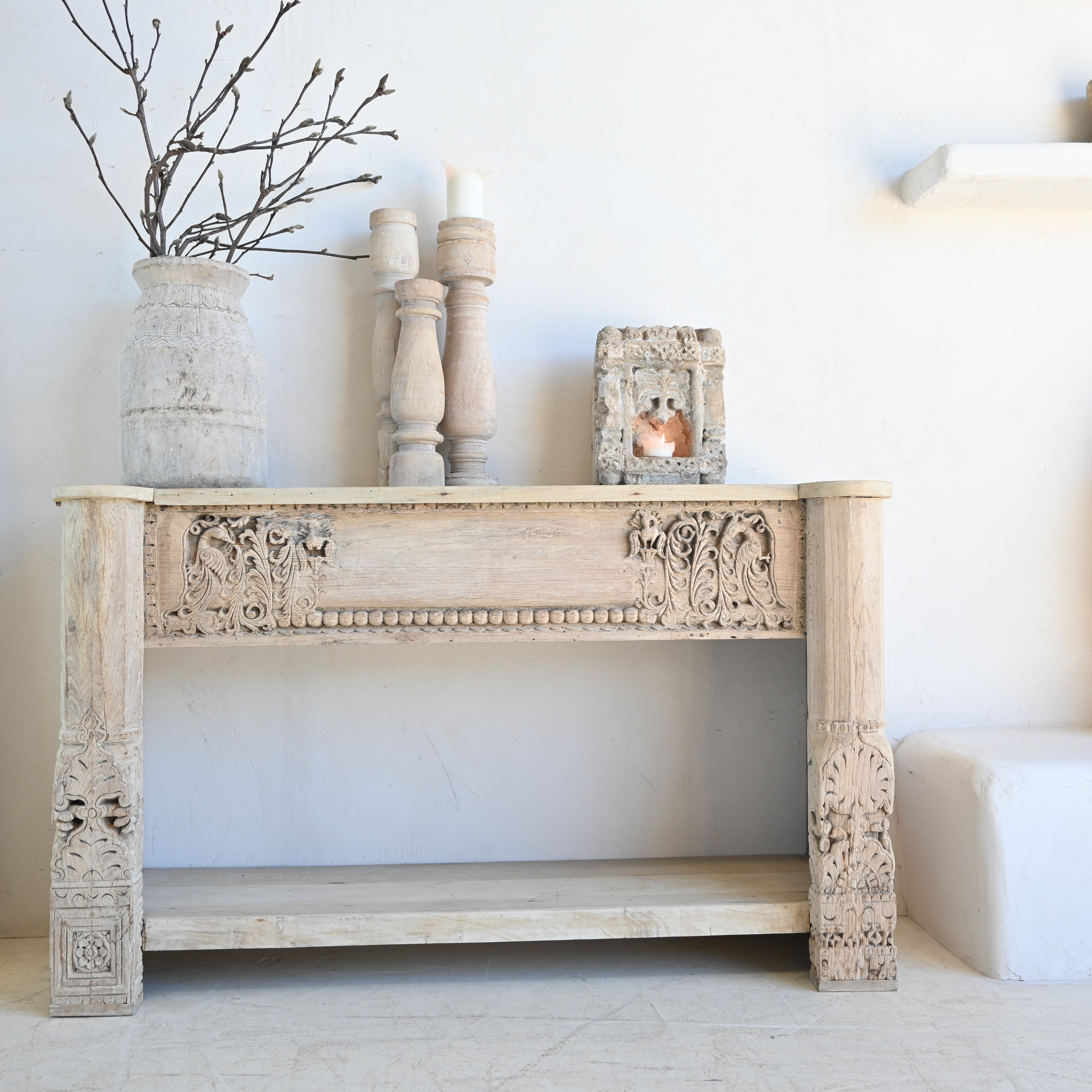 Decorative console table with ornate carvings against a white wall.