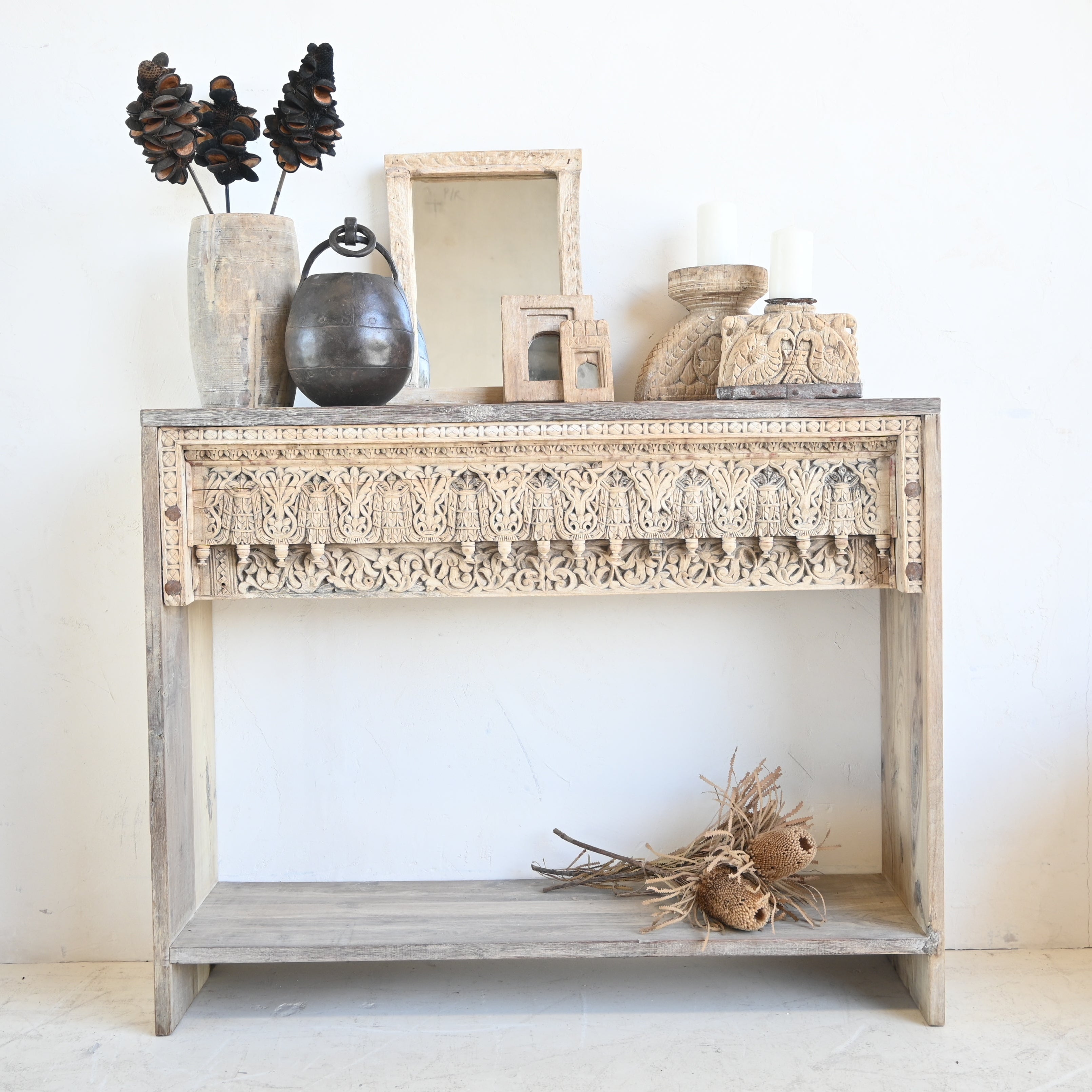 Decorative console table with carved patterns against a white wall