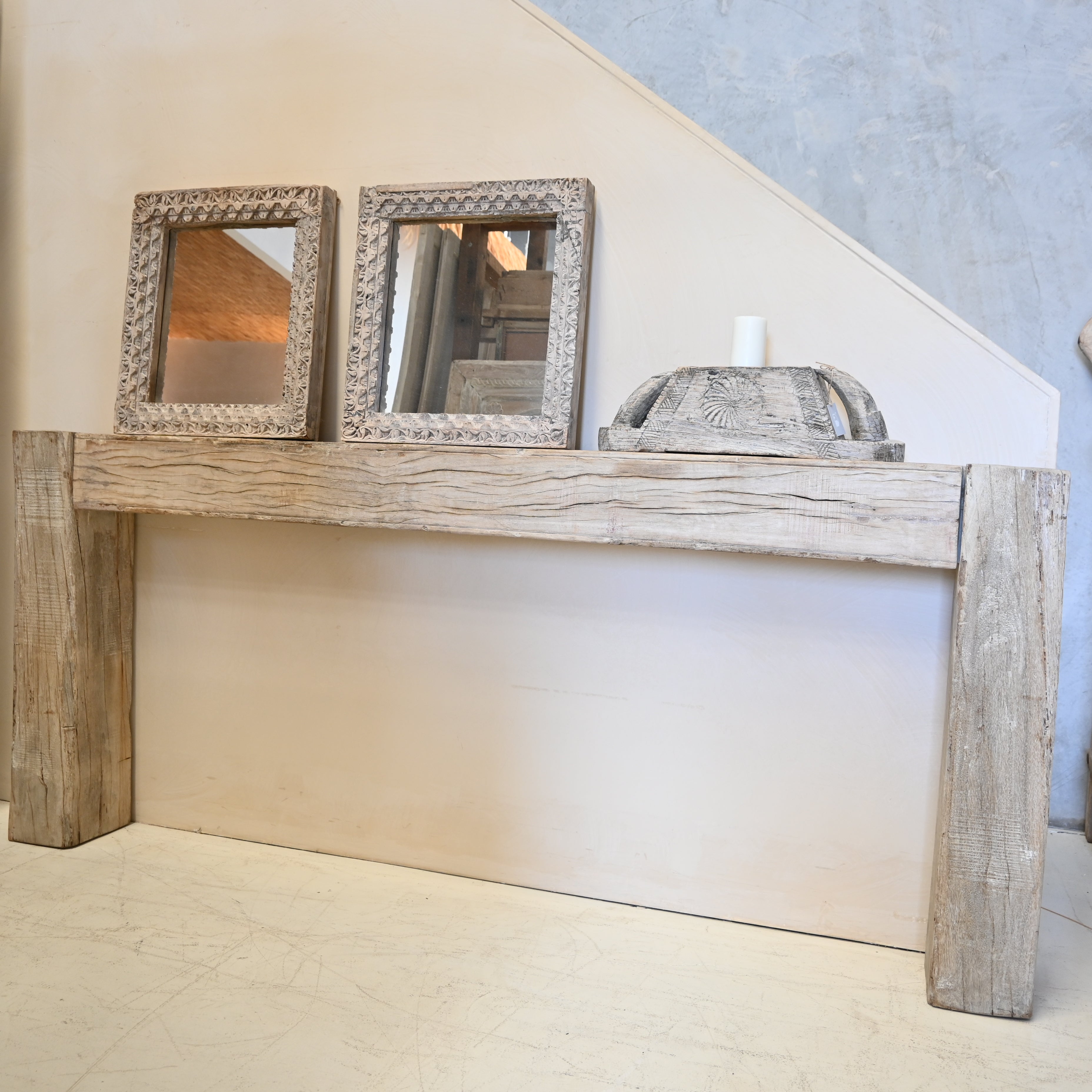 Wooden console table with two framed mirrors against a wall.