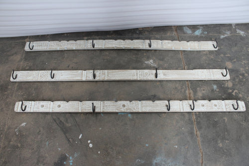 Three carved panels with hooks on a concrete floor 