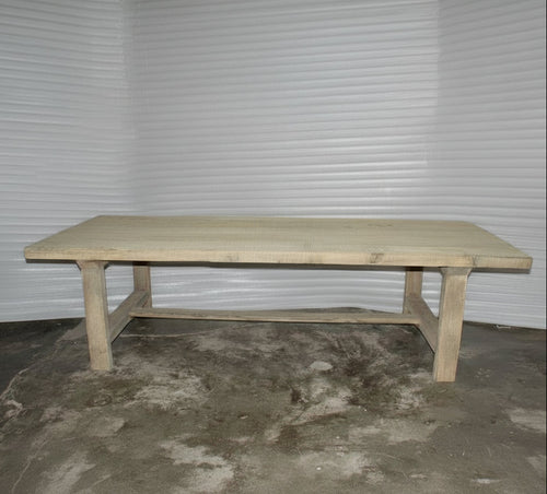 Wooden table on a concrete floor with a visible brand label.