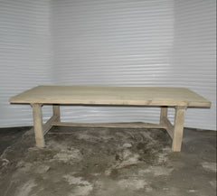 Wooden table on a concrete floor with a visible brand label.