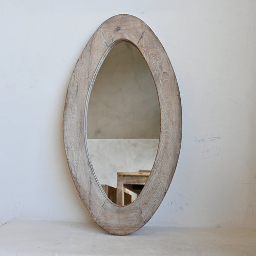 Oval wooden mirror on a white wall