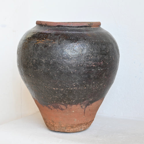 Black ceramic jar with a terracotta base on a white background