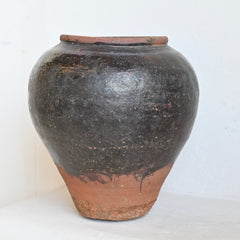 Black ceramic jar with a terracotta base on a white background