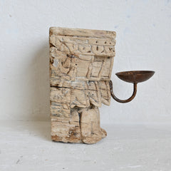 Decorative candle holder made from a wooden block with intricate carvings on a light gray background