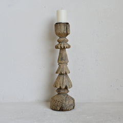 Wooden candle holder with a candle on a plain background