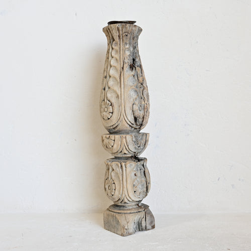 Decorative wooden candle holder with intricate carvings on a white background
