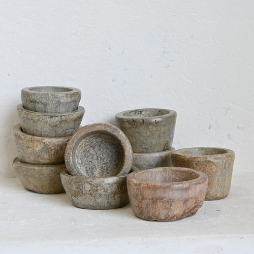 Set of stone bowls of various sizes on a white surface with a light gray background