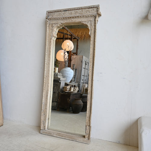 Decorative mirror with intricate frame on a white wall