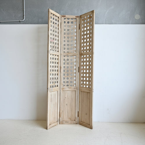 Wooden screen with lattice design panels on a white wall.