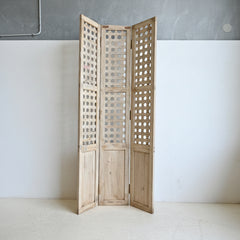 Wooden screen with lattice design panels on a white wall.