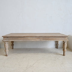 Wooden table with turned legs on a light wooden floor against a white wall