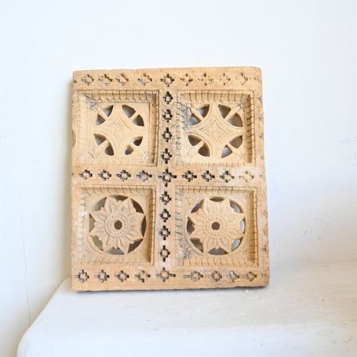 Decorative carved stone panel with geometric patterns on a white background