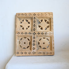 Decorative carved stone panel with intricate carvings on a white background