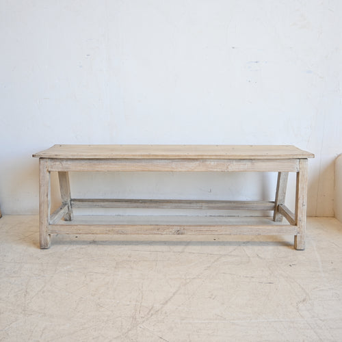 Wooden bench in a minimalistic room with white walls and floor.