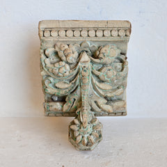Decorative wooden corbel candle holder with intricate carvings on a light background