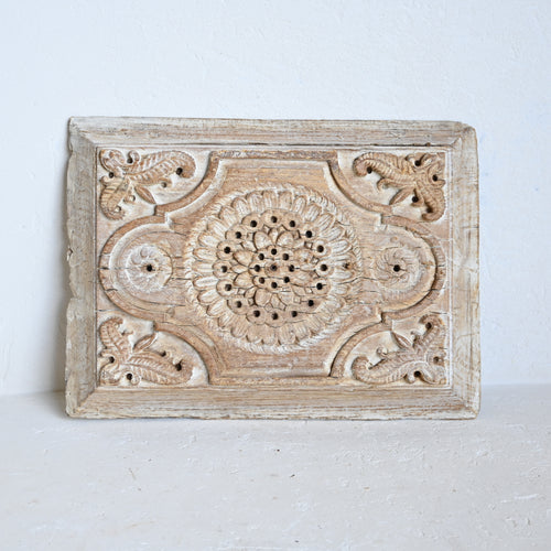 Decorative wooden panel with intricate carvings on a white background