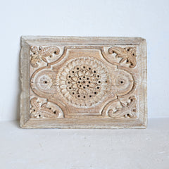 Decorative wooden panel with intricate carvings on a white background