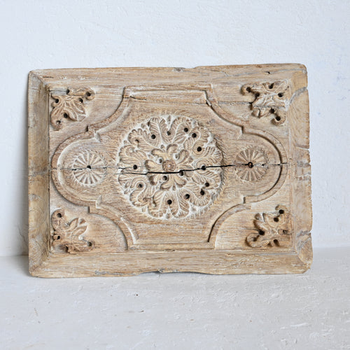 Decorative wooden panel with intricate carvings on a white background