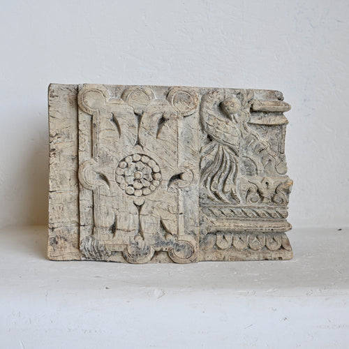 Decorative wooden panel with intricate carvings on a white background
