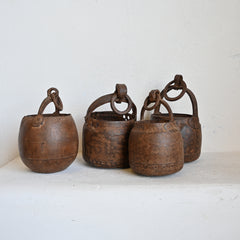 Four rustic wooden buckets with metal handles on a white surface.