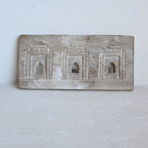 Wooden carved mirror plaque with  architectural designs on a white background