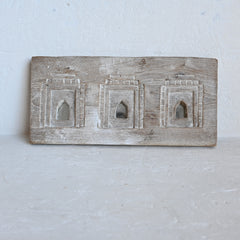 Wooden carved mirror plaque with  architectural designs on a white background