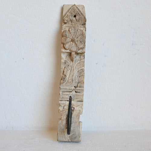 Decorative timber panel with intricate carvings  and a single hook on a white background