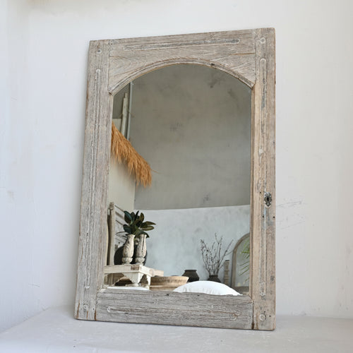 Wooden-framed mirror on a white wall with minimal decor