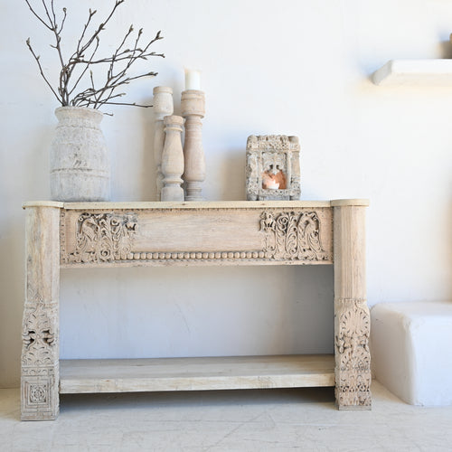 Decorative console table with ornate carvings against a white wall.