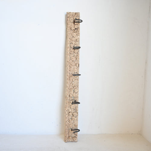 Vintage carved panel with metal hooks on a white background