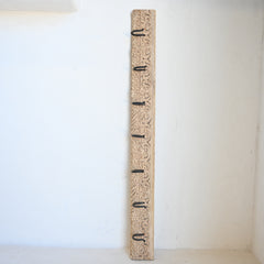 wooden vintage carved panel with black hooks against a white wall