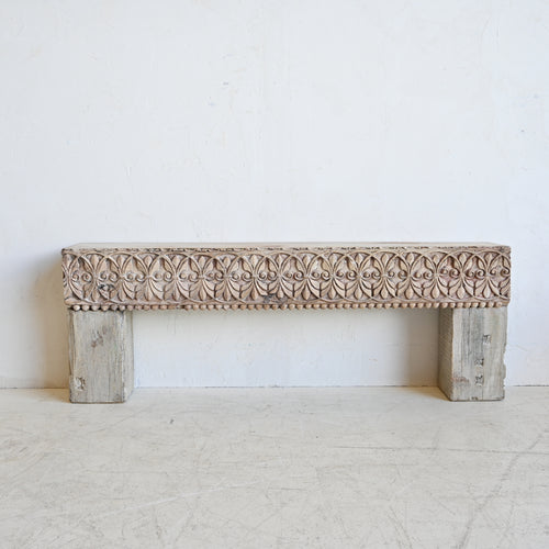 Carved wooden bench with intricate patterns on a white background