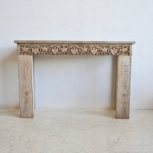 Wooden console table with intricate carvings on a white background