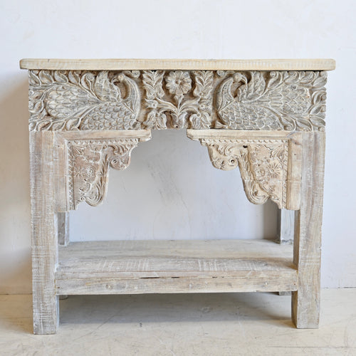 Carved wooden console table with intricate designs on a white background