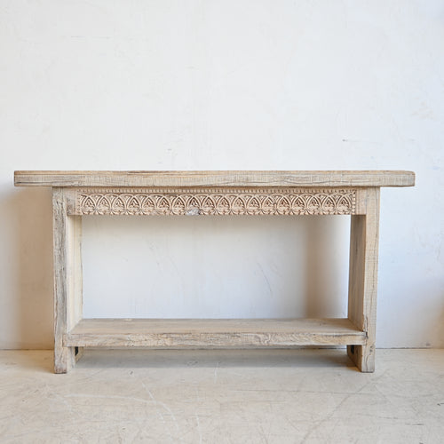 Wooden console table with intricate carvings on a white background