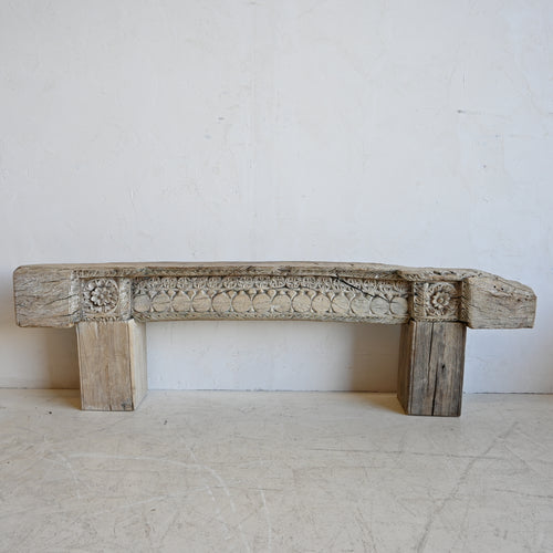 Decorative wooden beam bench with intricate carvings on a plain background