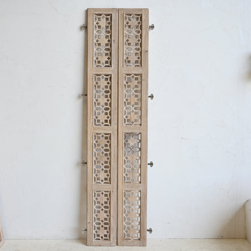 Wooden panel with decorative cut-out patterns on a white wall
