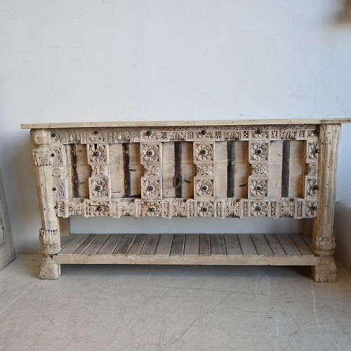 Carved wooden console table against a white wall