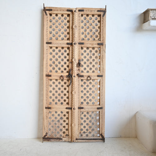 Decorative wooden door with intricate patterns on a white wall.