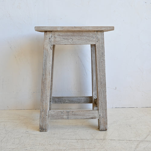 Wooden stool with a weathered finish on a white background