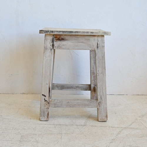 Wooden stool with a weathered finish on a white background
