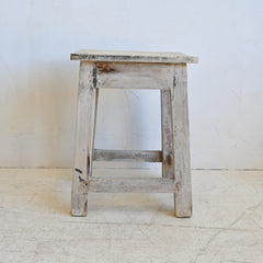 Wooden stool with a weathered finish on a white background