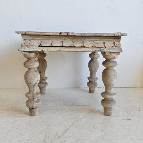 Vintage wooden table with turned legs on a white floor and wall