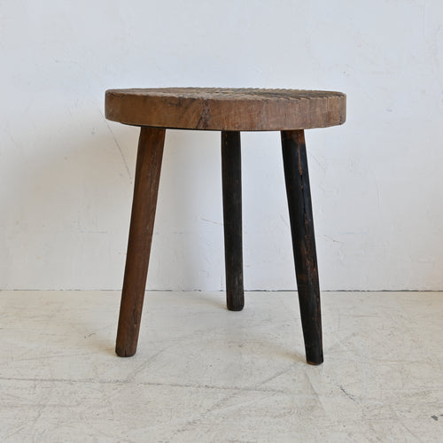 Wooden side table with a round top and three legs on a white floor.