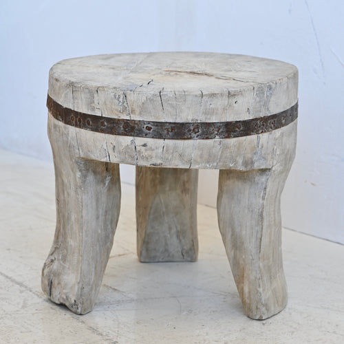 Wooden stool with a metal band on a light background