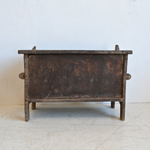 Vintage wooden chest with a rustic finish on a light gray floor.
