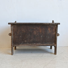 Vintage wooden chest with a rustic finish on a light gray floor.